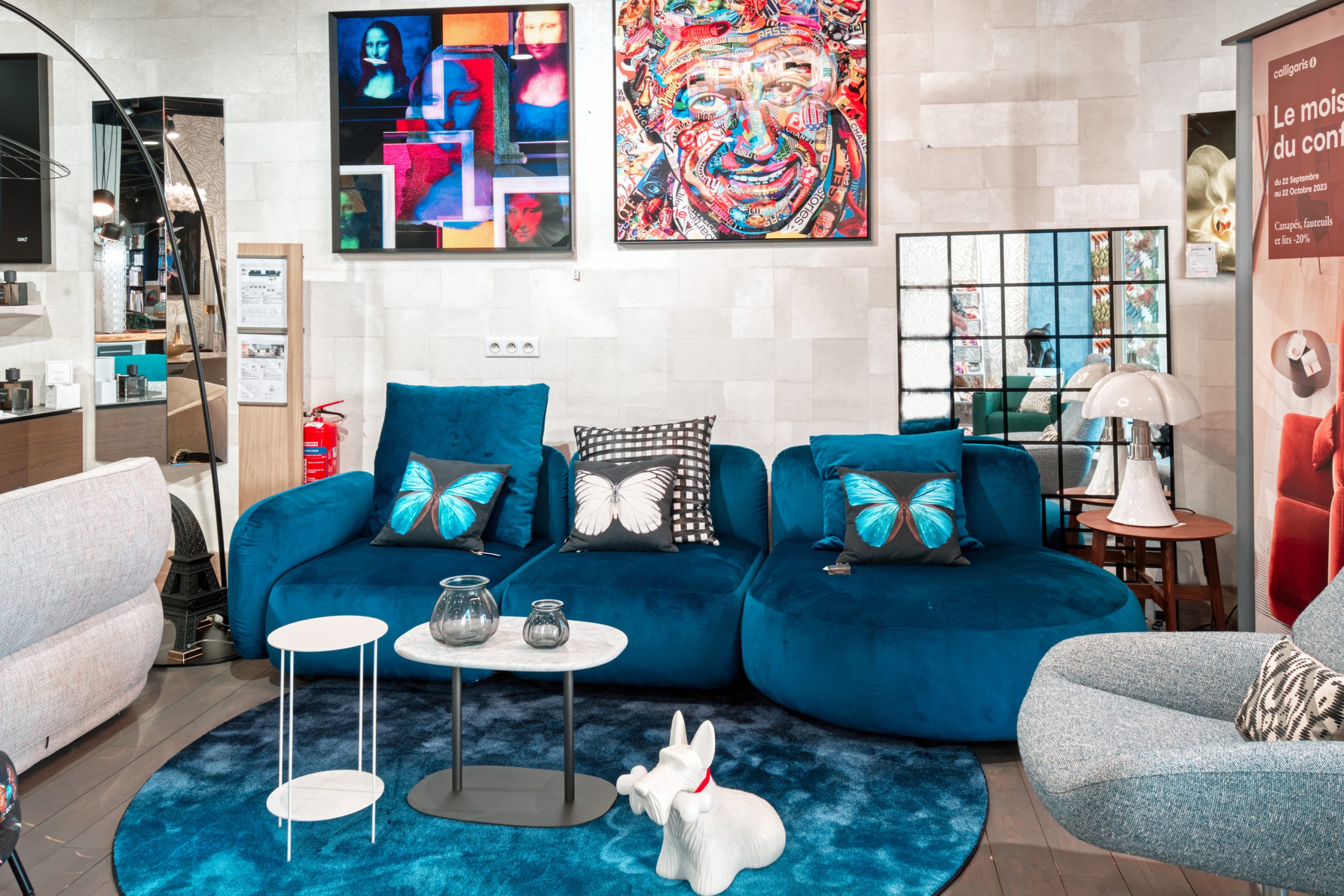 Salon avec un canapé bleu en velours et des coussins papillons